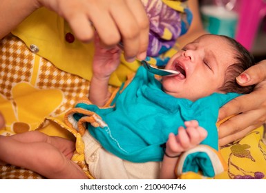 Close-up Of Caring Indian Mother Feeding Milk To Her A Newborn Baby With A Spoon. 