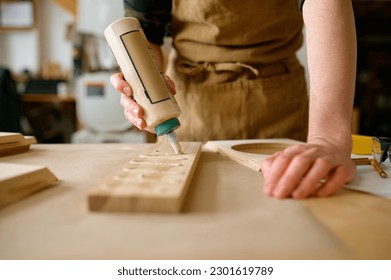 Closeup carpenter applying glue to board wooden timbers - Shutterstock ID 2301619789