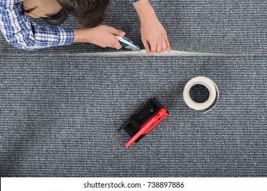 Close-up Of Carpenter Hand's Laying Carpet Using Cutter