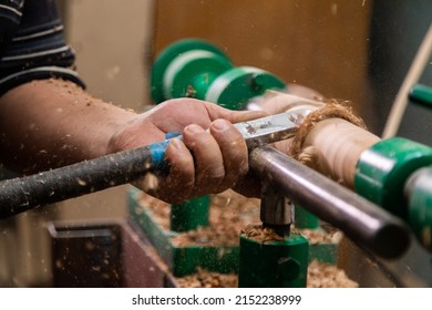 Closeup of carpenter turning wood on a lathe. Person carving chisel candlestick on a lathe