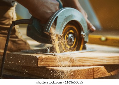 Close-up of a carpenter using a circular saw to cut a large board of wood