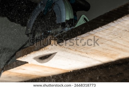 Close-up of a carpenter using a circular saw to cut a large board of wood 