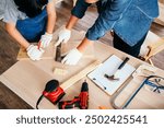 Close-up carpenters hands wearing work gloves draw the cutting line with a pencil on a wooden board. Construction industry, carpentry workshop. Carpenter small business. Carpentry concept.