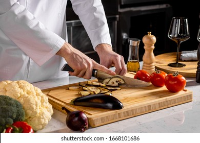 close-up caucasian chef-cook cut vegetables in kitchen. cook make vegetarian dish for restaurant visitors, man in white apron use sharp knife for better cutting