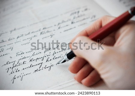 Close-up of a Caucasian female hand holding a fountain pen and writing a purchase contract in Czech language. Concept for old law, legal issues and old handwritten documents.