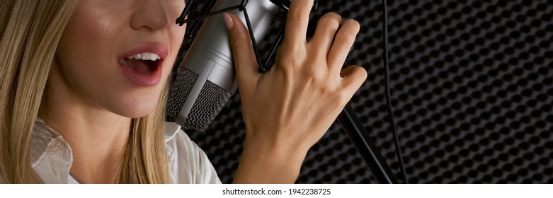 Closeup caucasian female hand and mouth, singing in front of black soundproofing walls. Musicians producing music in professional recording studio.