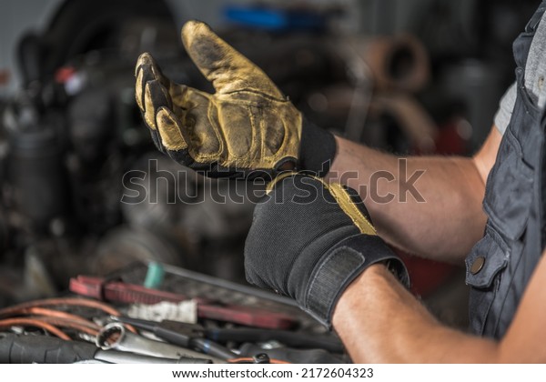 Closeup of\
Caucasian Mechanic\'s Dirty Work Gloves After a Day of Hard Work at\
the Car Shop Station. Automotive\
Theme.