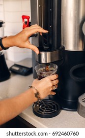 Closeup Of Caucasian Woman Barista Hands Making Pouring Coffee From Coffee Machine In Plastic Transparent Cup. Toned With Film Filters