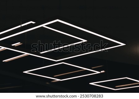 A close-up of a ceiling fixture, with multiple rows of white, rectangular lights, creating a geometric pattern.
