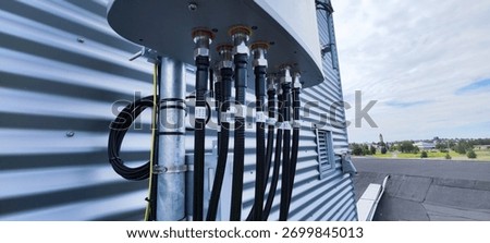 Close-up of a cellular base station panel on a rooftop with coaxial feeders and connectors, modern telecom infrastructure.