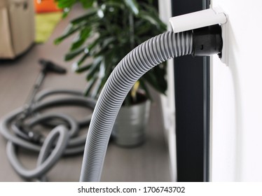 Closeup of central vacuum cleaner hose plugged in to wall inlet socket. View in to room with central vacuum cleaner. - Shutterstock ID 1706743702