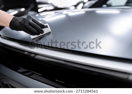 Close-up of ceramic coating being applied to a matte car paint surface by a gloved detailer, showing careful technique, surface protection and professional car detailing dedicated to matte finishes.