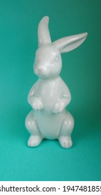 close-up ceramic figurine of a blue Easter bunny on a turquoise background front view . Easter symbol