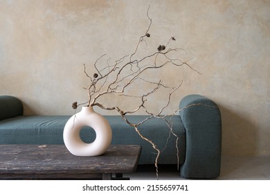 Closeup of ceramic vase with dry branches on ancient table. Room with textured walls and decor interior design. Home comfort. Photo studio zone