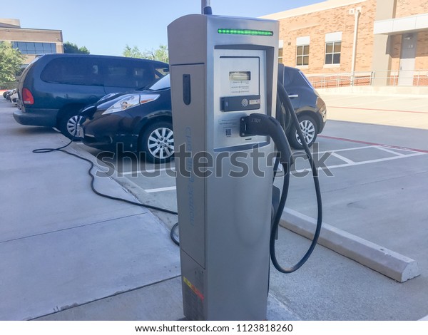 Close-up charging\
station with charger plugged into the electric car. Rechargeable\
batteries vehicle refuel at parking lots. Concept of future\
automobile and\
transportation
