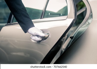 Closeup of Chauffeur opening car door with glove - Shutterstock ID 707662540