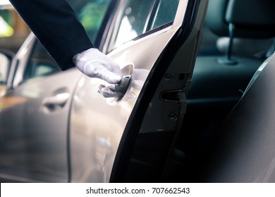 Closeup of Chauffeur opening car door with glove - Shutterstock ID 707662543