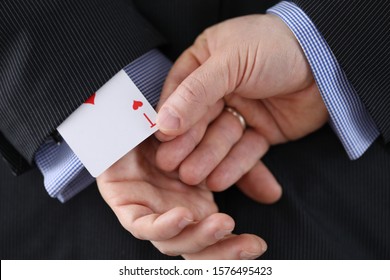 Close-up of cheater hands pulling ace card out of sleeve with crossed arms behind. Gamer with strong addiction to games. Bribe casino and dishonesty concept
