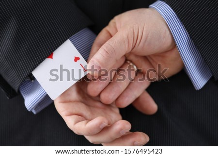 Close-up of cheater hands pulling ace card out of sleeve with crossed arms behind. Gamer with strong addiction to games. Bribe casino and dishonesty concept