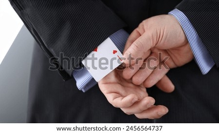 Close-up of cheater hands pulling ace card out of sleeve with crossed arms behind. Gamer with strong addiction to games. Bribe casino and dishonesty concept