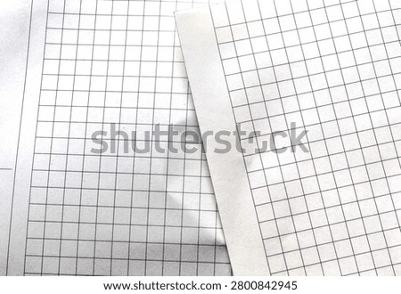 Close-up of checkered notebook paper texture with a subtle crease and shadows.