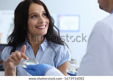 Close-up of cheerful lady looking at doctor with smile. Beautiful female at consultation with plastic surgeon. Silicone implant surgery and anaplasty concept