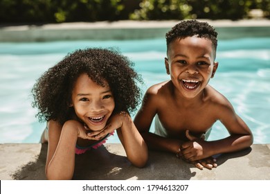 Closeup of cheerful small boy and girl enjoying in swimming pool. Cute brother and sister leaning on pool edge and smiling. - Powered by Shutterstock