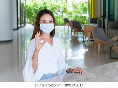 Closeup Of Cheerful Young Asian Girl With Protective Face Mask Showing Fine In Sign Language Hand And Smiling At Camera. New Normal, Health Care Concept.