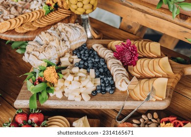 A closeup of a cheeseboard with a selection of cheese, blueberries and fresh bread - Powered by Shutterstock