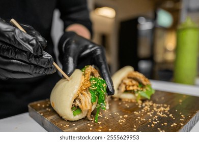 A close-up of a chef in black gloves preparing steamed buns filled with chicken and greens. The dish is garnished with sesame seeds, showcasing an appetizing culinary presentation. - Powered by Shutterstock