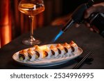 Close-up of a chef carefully searing a nigiri sushi with a culinary blowtorch.