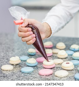 Closeup Chef With Confectionery Bag Squeezing Cream Filling To Macarons Shells 