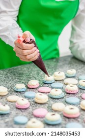 Closeup Chef With Confectionery Bag Squeezing Cream Filling To Macarons Shells 