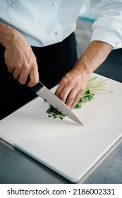 Close-up Of A Chef Finely Chopping Herbs In A Professional Kitchen