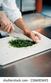 Close-up Of A Chef Finely Chopping Herbs In A Professional Kitchen