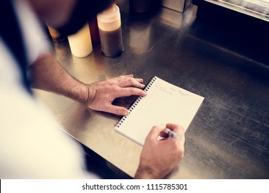 Closeup of chef hand writing menu on metal cooking table - Powered by Shutterstock