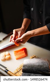 Closeup Of Chef Hands Preparing Japanese Food. Japanese Chef Making Sushi At Restaurant. Young Chef Serving Traditional Japanese Sushi Served On A Cuting Board In Lighting Studio . 