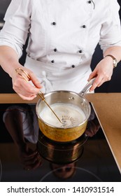 Close-up Of Chef Mixing Milk For Cake For Baking Cake And Making Chocolate. Hands Cook Stir Milk Whisk In A Metal Bucket Warming It On The Stove