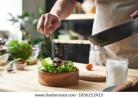 Close-up of chef putting fried meat on the plate with vegetables he cooking dish from chef