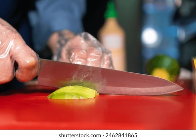 Close-up of the chef slicing a ripe avocado on a red board with a large knife. - Powered by Shutterstock