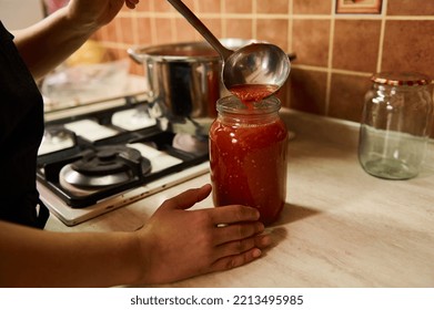 Close-up. Chef using a ladle, pours boiling juice of organic juicy tomatoes into a sterilized canning can. Preparing tomato sauce or passata. Preserving homegrown vegetables for winter. Canned food - Powered by Shutterstock
