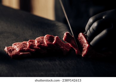 Close-up of a chef wearing black gloves expertly slicing meat, showcasing culinary precision and hygiene - Powered by Shutterstock