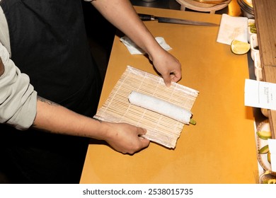 Close-up of a chef's hands carefully rolling a sushi roll on a bamboo mat - Powered by Shutterstock