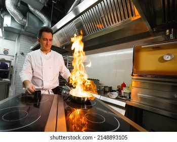 Close-up of the chef's hands cooking food on fire. The chef burns food in a professional kitchen - Powered by Shutterstock