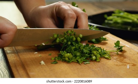 Close-up of a chef's hands with a knife slicing parsley on a cutting board. Side view. Delicious and healthy food - Powered by Shutterstock