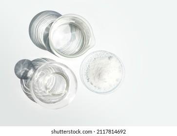 Closeup chemical ingredient on white laboratory table. Di-Ammonium Prosphate in Chemical Watch Glass place next to beaker with alcohol and Erlenmeyer flask. Top View