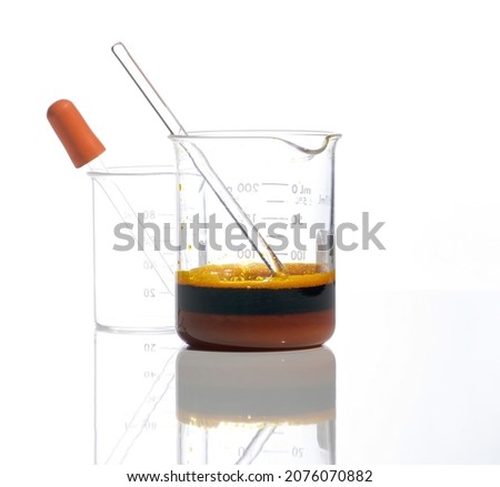 Closeup chemical ingredient on white laboratory table. Ferric Chloride Liquid with stirring rod in Beaker. Side View