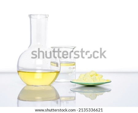 Closeup chemical ingredient on white laboratory table. Sulfur Powder in Chemical Watch Glass place next to Aluminium chloride liquid, oil and alcohol in Beaker. Side View