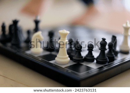 Close-up of a chessboard with a focused queen chess piece in the foreground and other blurred pieces, symbolizing strategy, competition, and intellect.
