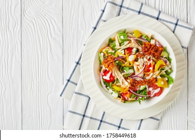 Close-up Of Chicken Club Salad With Fried Bacon, Romaine Lettuce Shredded Chicken Breast, Cheddar Cheese, Tomatoes And Yogurt Dressing In A White Bowl On A Wooden Table, Flat Lay, Free Space